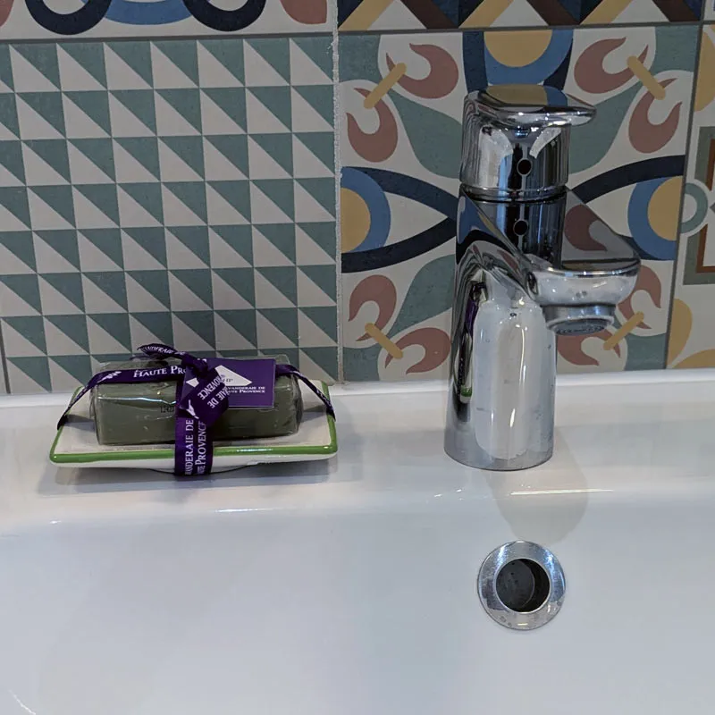 Porte-savon olive rectangulaire avec savon présenté à coter du robinet sur lavabo